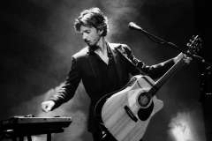 Luca Zabbini playing acoustic guitar with PFM, black and white